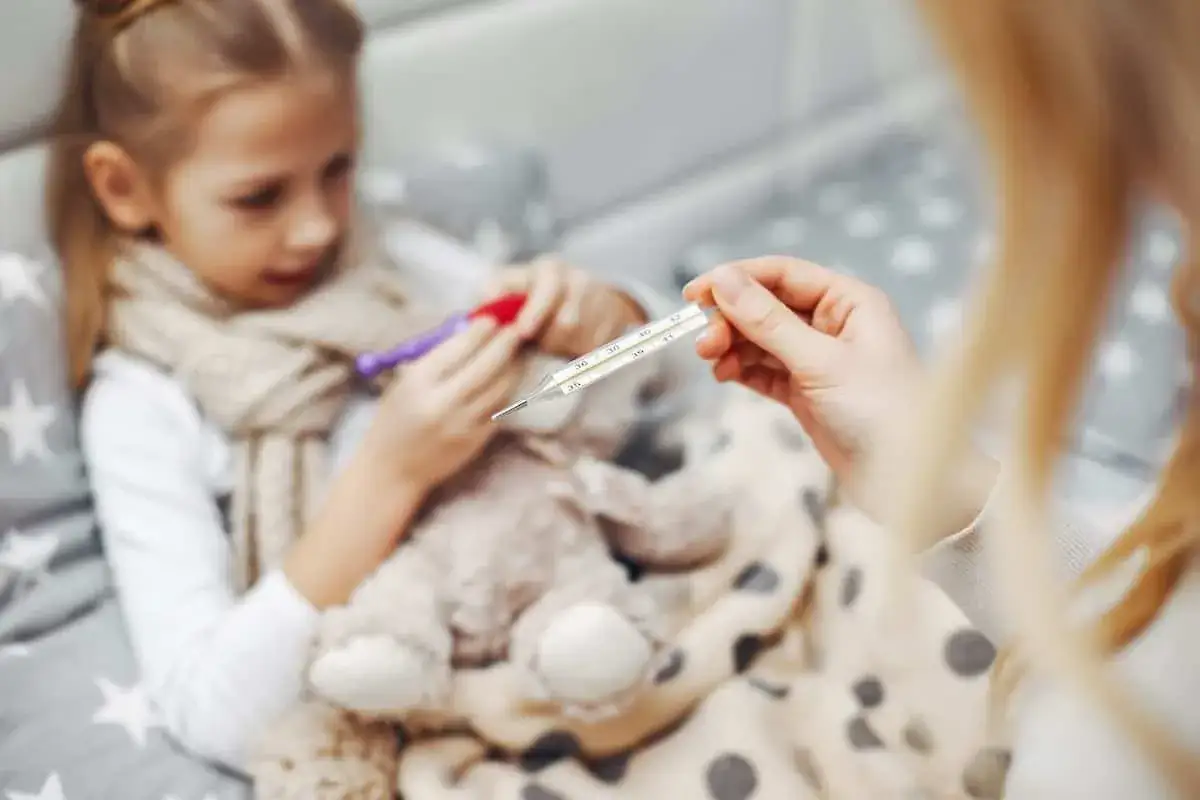 Dziecko z gorączką, mama mierzy temperaturę. Objawy rotawirusa mogą być groźne.